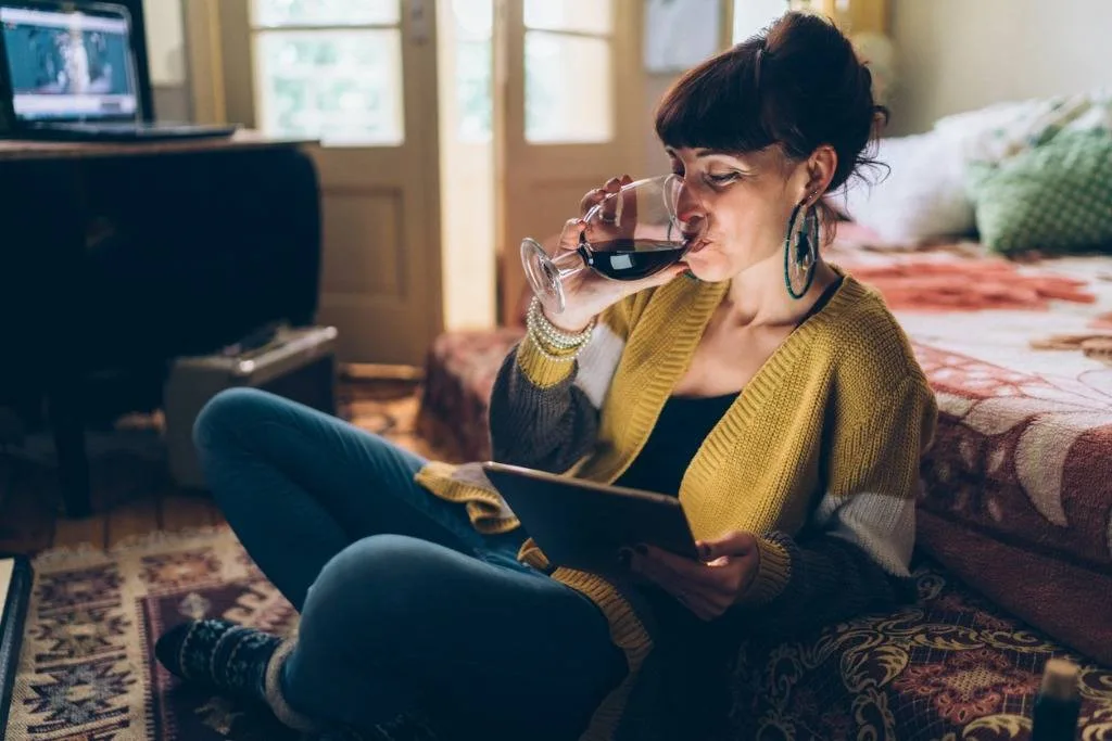 femme buvant du vin et lisant un livre électronique