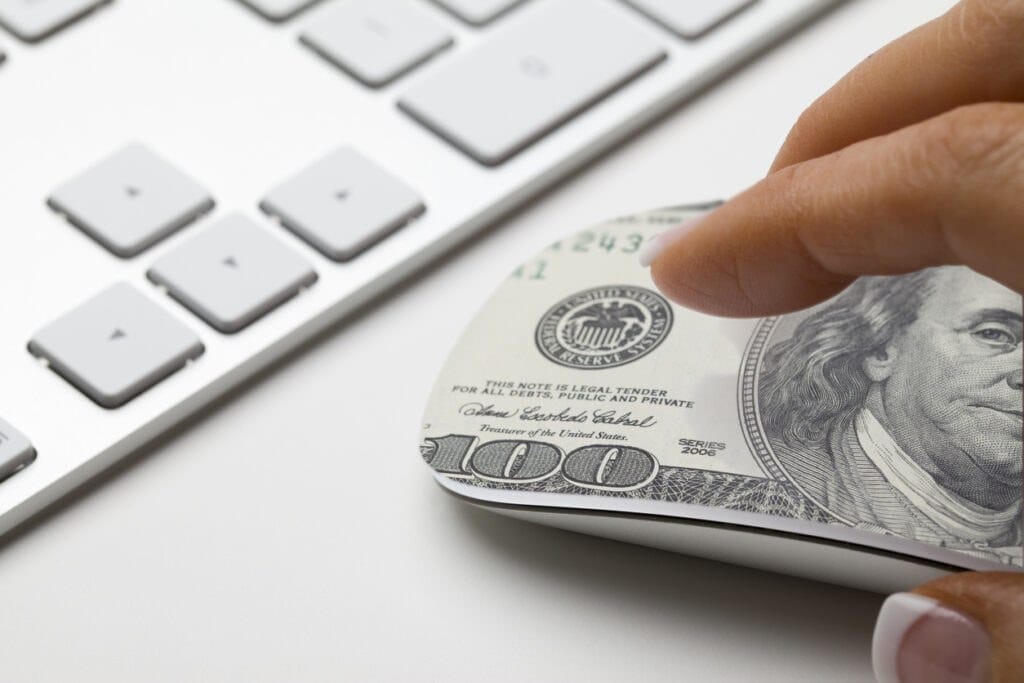 Hand on mouse with 100 dollar bill on it. Concept for affiliate marketing or e-commerce.