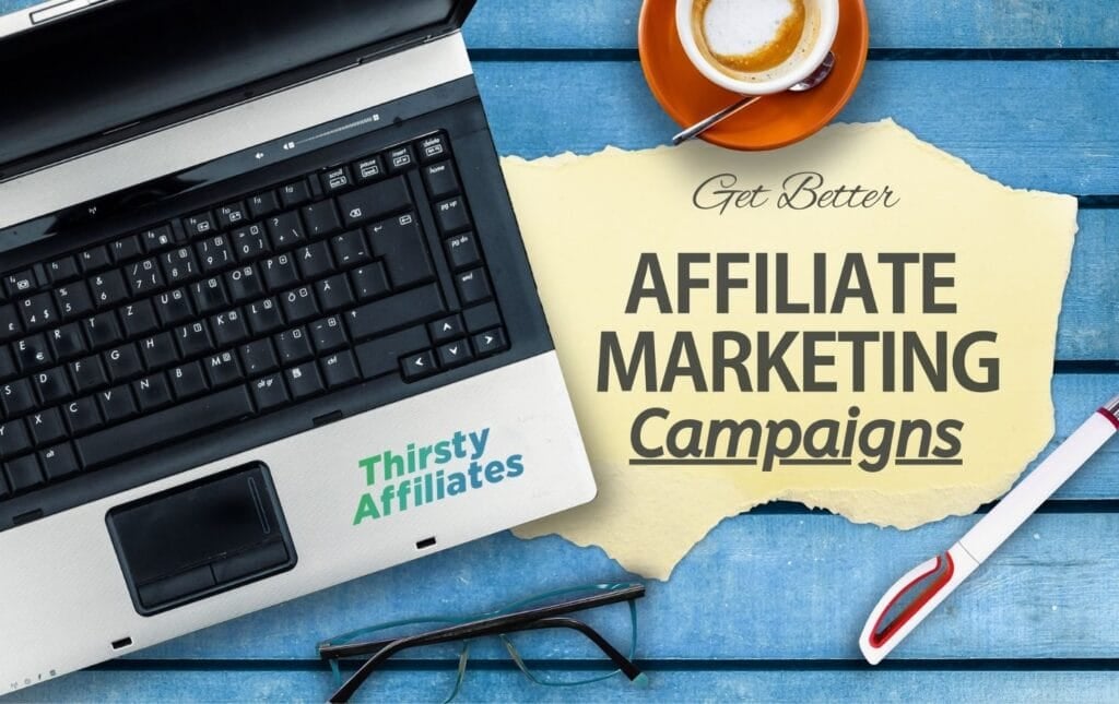 Texto "Consigue mejores campañas de marketing de afiliación" delante de un espacio de trabajo abarrotado. El logotipo de Thirsty Affiliates está presente.